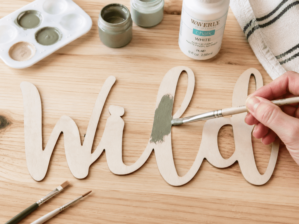 applying first coat of paint on wooden craft